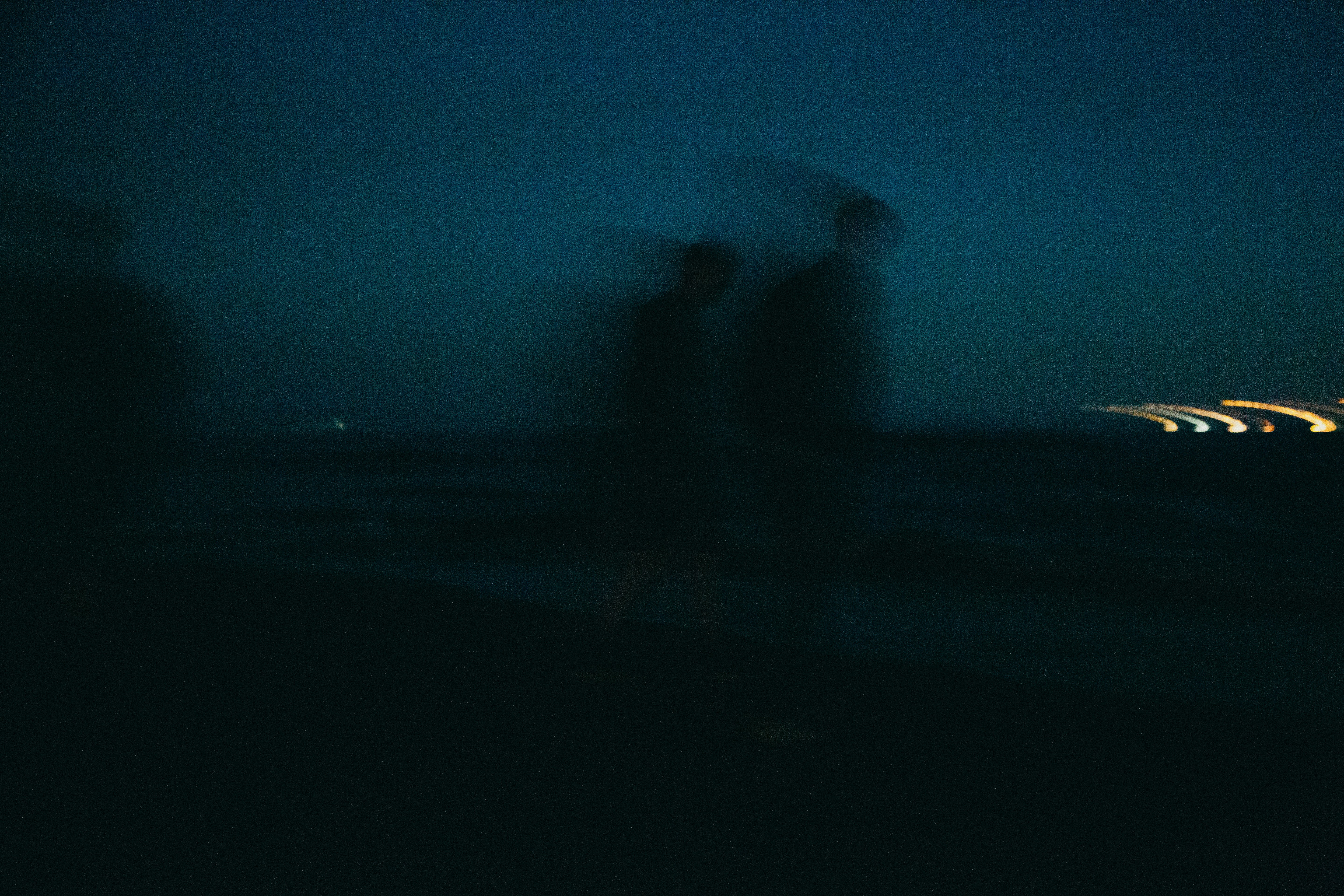 silhouette of person standing on beach during night time